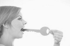 Frau steckt sich einen übergroßen Schlüssel in den Mund